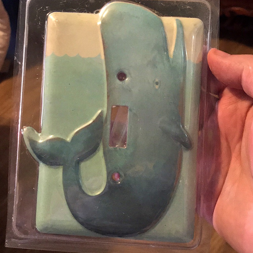 A whale shaped light switch plate still in its packaging.